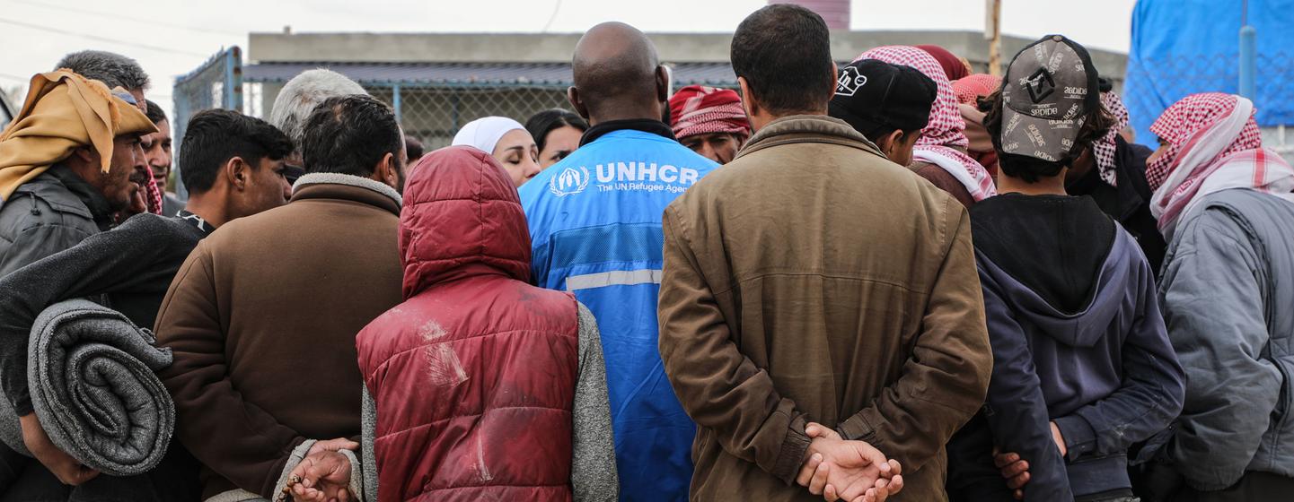 Un employé du HCR fournit des informations à un groupe de personnes déplacées dans le camp d'Areesha, au nord-est de la Syrie...