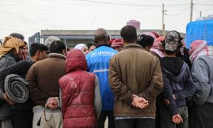 A UNHCR staff member provides information to a group of internally displaced people at Areesha camp, northeast Syria...