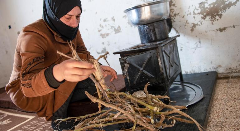 Una mujer alimenta con ramitas un calefactor para calentar su casa en la zona rural de Damasco.