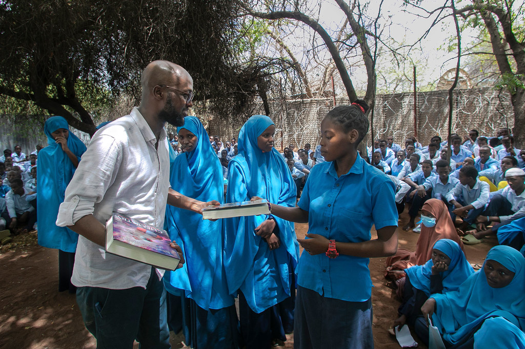 Le militant et journaliste réfugié Abdullahi Mire (à gauche), lauréat mondial de la distinction Nansen pour les réfugiés 2023 du HCR, distribue des livres à des élèves réfugiés dans une école secondaire à Dadaab, au Kenya.