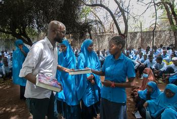 الصحفي والناشط عبد الله ميري يوزع كتبا على طلاب لاجئين في مدرسة ثانوية.