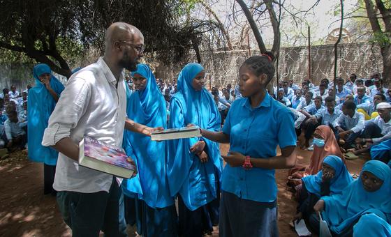 Refugee activist and journalist Abdullahi Mire (left), the Global Laureate of the 2023 UNHCR Nansen Refugee Award, distributes books to refugee students at a secondary school in Dadaab, Kenya.