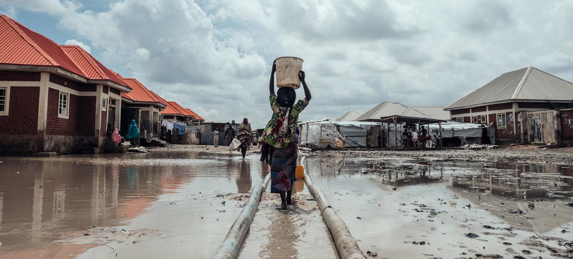 Milhões estão deslocados em toda a Nigéria devido a conflitos, impactos das alterações climáticas e catástrofes naturais. Nesta foto de arquivo, uma menina leva água para seu abrigo em um campo de deslocados internos no nordeste do país