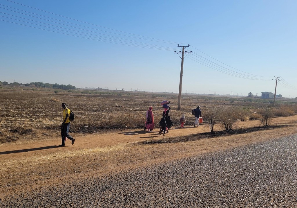 Des enfants et des familles fuient à pied après l'éruption de combats à Wad Madani, dans l'Etat d'Al Jazira.