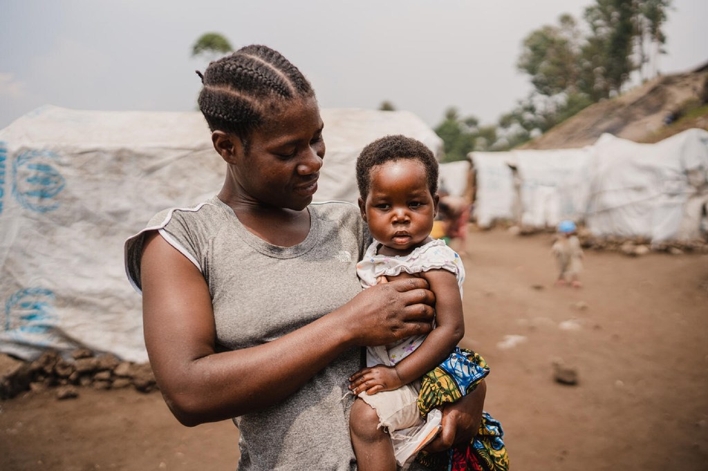 Une mère tient sa jeune fille dans ses bras dans un camp de réfugiés du Nord-Kivu, en République démocratique du Congo, après une consultation dans une clinique mobile de UNICEF .