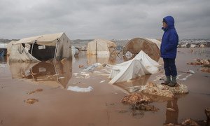 A child looks over a flooded area of Kafr Losin Camp in northwestern Syria.