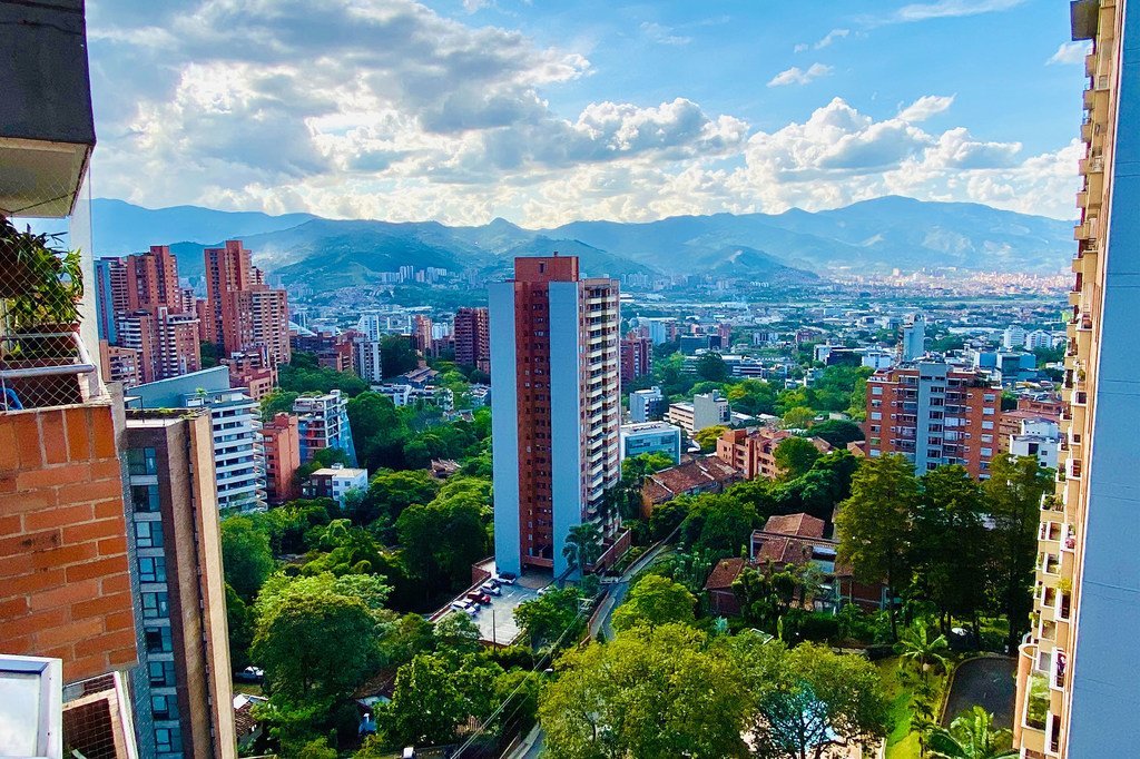 Vista del Corredor Verde en Medellín, Colombia, que muestra una mezcla de rascacielos y espacios verdes con montañas al fondo.