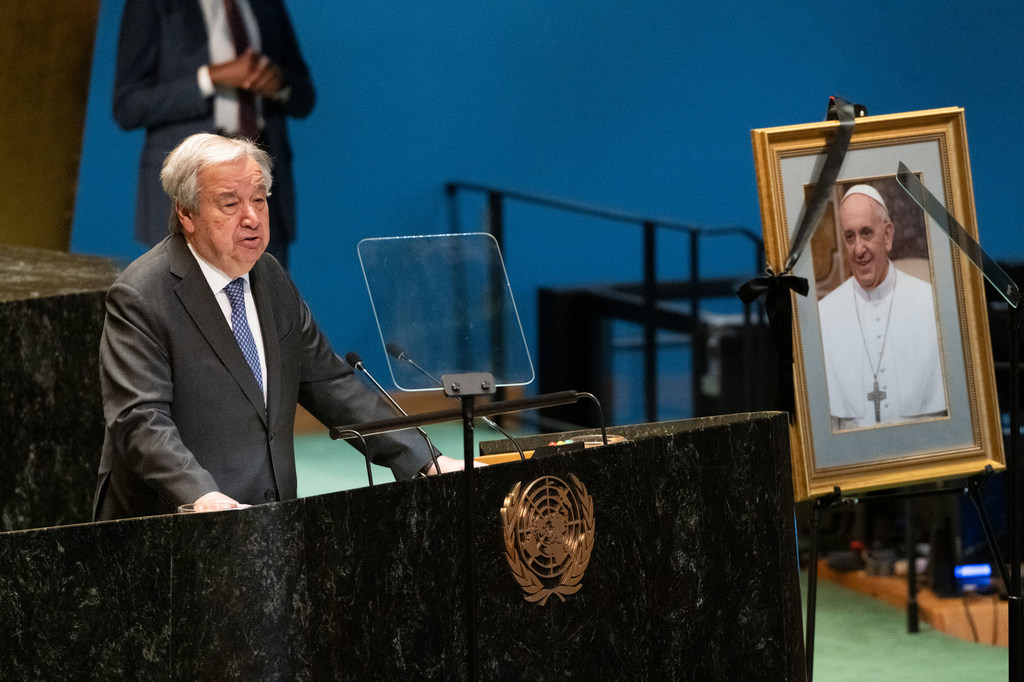 Katibu Mkuu UN António Guterres akizungumza kwenye jukwaa wakati wa hafla ya Mkutano Mkuu UN katika Kumbukumbu ya Mtakatifu Papa Francis, huku picha ya Papa ikionyeshwa karibu.