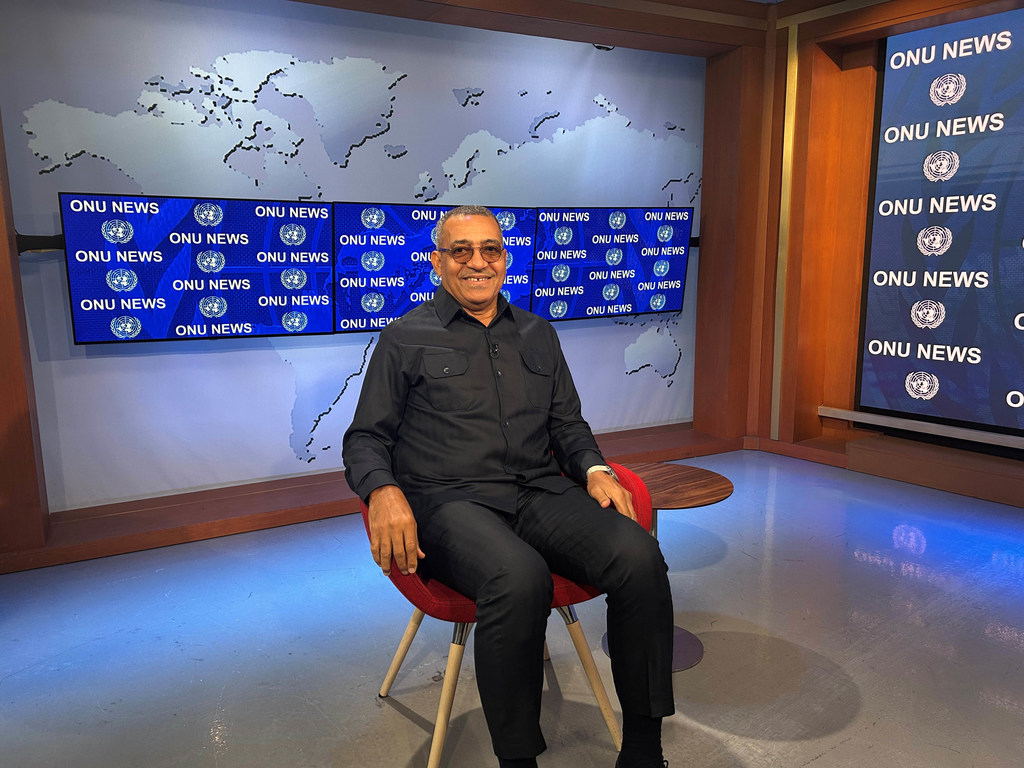 O presidente Carlos Vila Nova, de São Tomé e Príncipe, está sentado em uma cadeira vermelha durante uma entrevista em um estúdio de televisão, com telas da ONU News ao fundo.