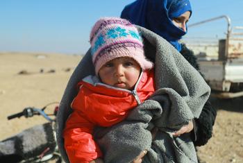ARCHIVO: Una madre y su hijo esperan su kit de ayuda para el invierno en un asentamiento informal en la zona rural del este de Raqqa, en Siria. 