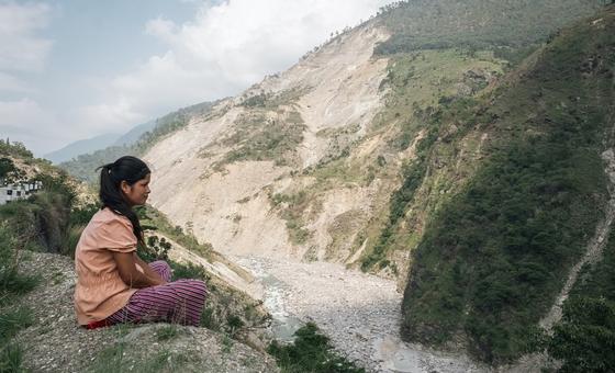 Dans l'ouest du Népal, une fille est assise au bord d'une falaise, surplombant un glissement de terrain massif provoqué par les pluies de mousson de 2023.