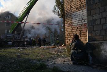 Un habitant près des ruines d'un immeuble résidentiel à Kyïv, regarde les équipes d'urgence rechercher des survivants après une frappe de missile.