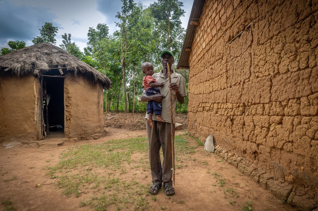 Mkulima wa tumbaku Dawin Sionyonyo Lusakia kutoka kaunti ya Bungoma, Kenya, amesimama na mtoto katika mazingira ya kijijini.