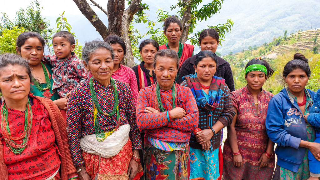नेपाल की कुछ महिलाएं और बच्चे ग्रामीण, सीढ़ीदार परिदृश्य में एक तस्वीर के लिए पोज दे रहे हैं। धनमाया थामी बीच में बाहें मोड़े खड़ी हैं।
