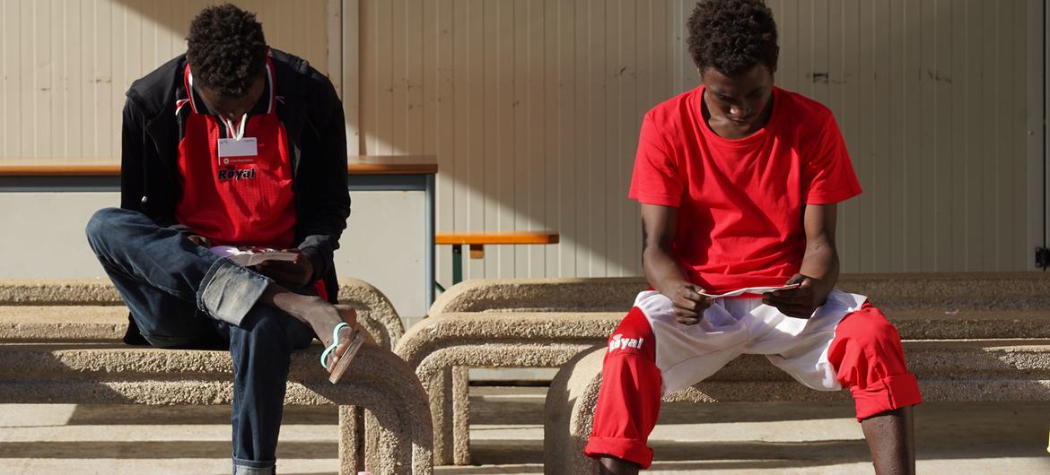 Des adolescents migrants non accompagnés lisent des brochures d'information à Lampedusa, en Italie, après avoir traversé la Méditerranée.
