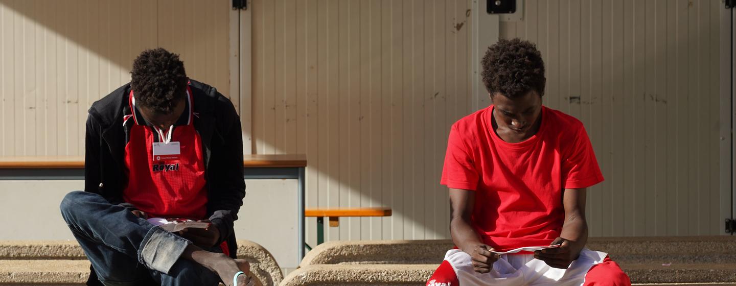 Des adolescents migrants non accompagnés lisent des brochures d'information à Lampedusa, en Italie, après avoir traversé la Méditerranée.