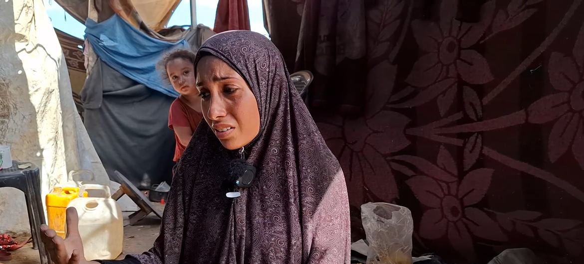 En la imagen se ve a una mujer palestina desplazada en Gaza junto a su marido herido y un niño pequeño en su refugio provisional.
