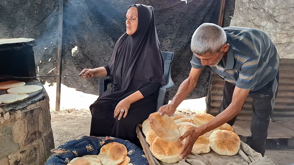 Umm Mohammed Abu Zuaiter and her husband bake bread at a clay oven in Gaza.