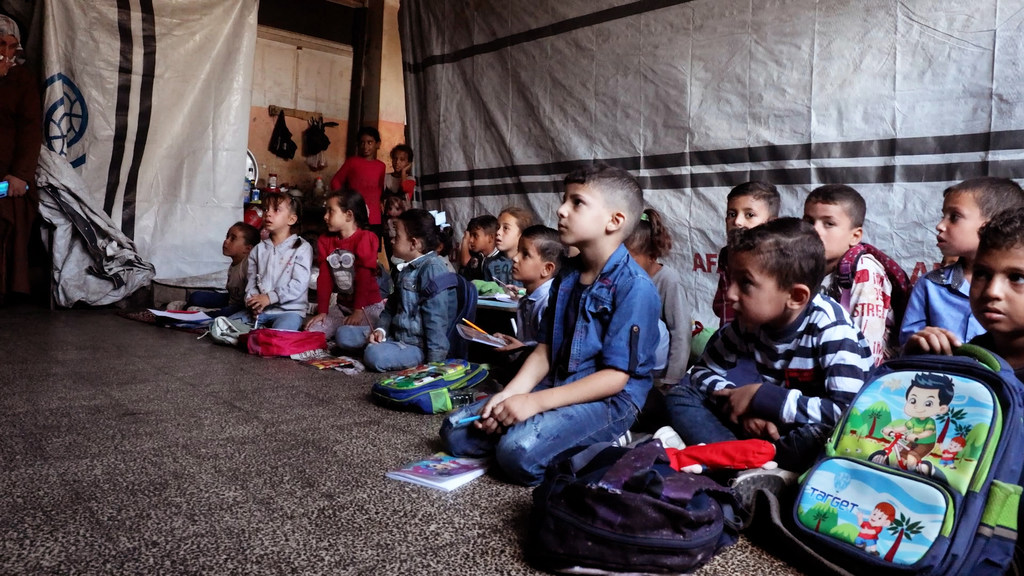 طلاب يجلسون على الأرض أثناء حضورهم الدروس في مدرسة دير البلح الابتدائية المشتركة التي تديرها الأونروا. طلاب يجلسون على الأرض أثناء حضورهم الدروس في مدرسة دير البلح الابتدائية المشتركة التي تديرها الأونروا.
