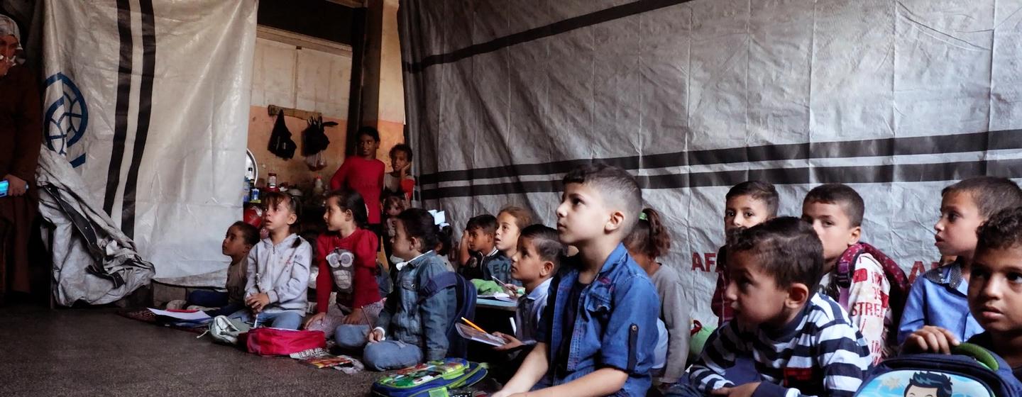 Des élèves palestiniens sont assis par terre dans une salle de classe d'une école de l'UNRWA à Deir al-Balah, dans la bande de Gaza.