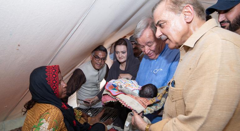 在为灾民搭建的临时帐篷中，秘书长古特雷斯（左）怀抱一名婴儿，他的右侧是巴基斯坦总理谢里夫。 