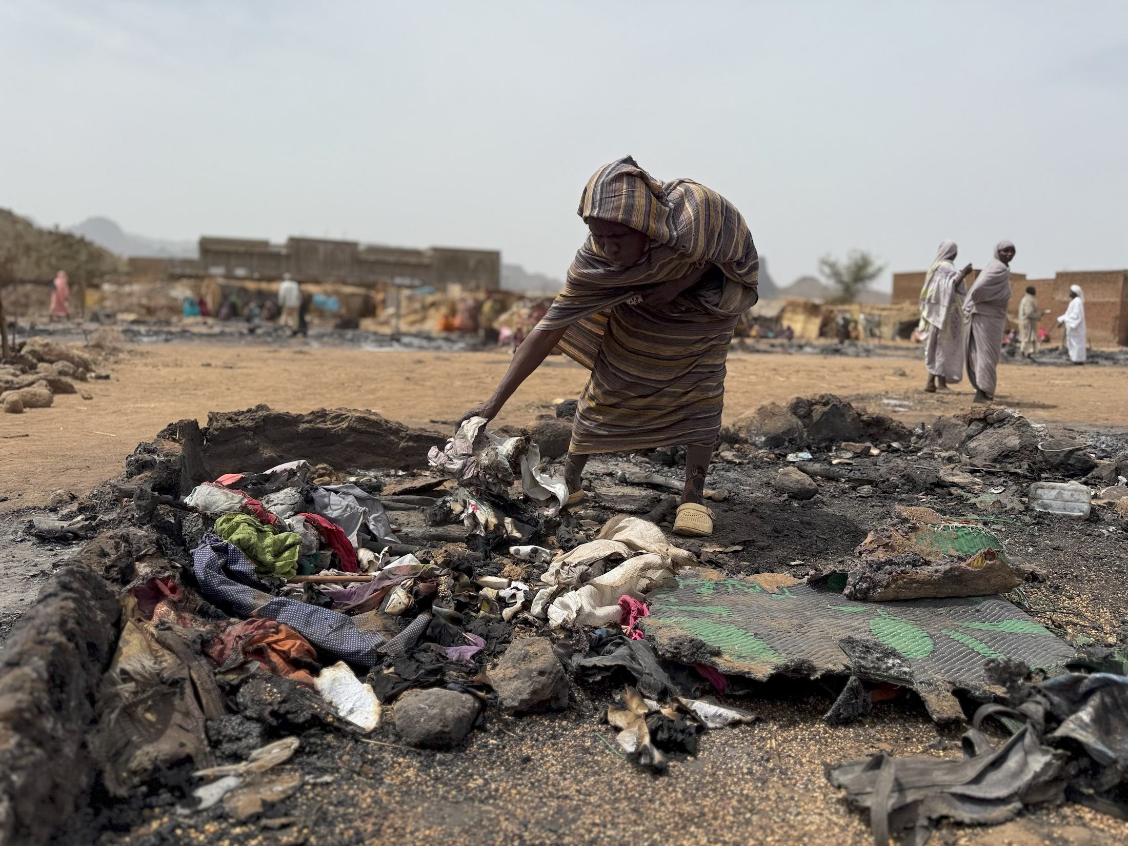 Une femme fouille les restes brûlés de son abri dans un camp de déplacés au Darfour, au Soudan.