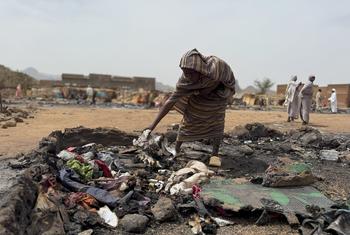 Una mujer busca entre los restos quemados de su refugio en un campo de desplazados de Darfur, Sudán.
