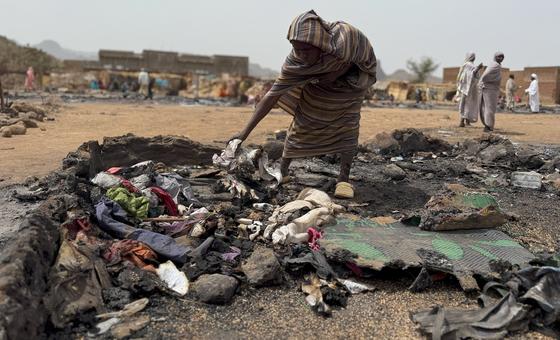 A woman searches through the burnt remains of her shelter at a displacement camp in Darfur, Sudan.