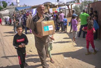 غزہ میں ساحلی راستے سے پہنچنے والی انسانی امداد میں توانائی سے بھرپور بسکٹ بھی شامل ہیں جن کا ڈبہ یہ فلسطینی خاندان وصول کر کے لا رہا ہے۔