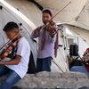 A boy and two girls playing music inside a tent in Gaza.
