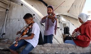 A boy and two girls playing music inside a tent in Gaza.