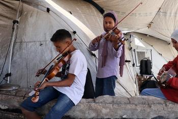 A boy and two girls playing music inside a tent in Gaza.