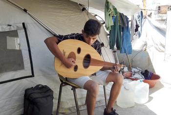 Un garçon joue de la musique à l'intérieur d'une tente à Gaza.