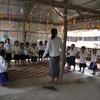 Uma professora está em uma sala de aula na zona rural do Camboja com um grupo de jovens alunos.