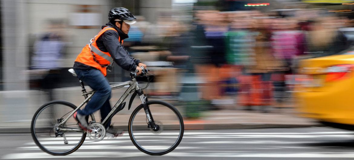 Un homme porte un casque et un gilet réfléchissant en faisant du vélo à Manhattan, New York.