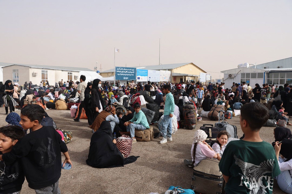 Los afganos que regresan al país se reúnen con su equipaje en el paso fronterizo de Islam Qala, a la espera en un refugio provisional.