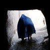 Une Afghane vêtue d'une burqa bleue traverse une ruelle étroite à Hérat.