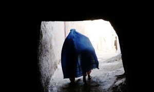 An Afghan woman in a blue burqa walks through a narrow alleyway in Herat.