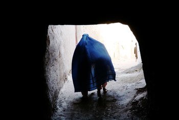 An Afghan woman in a blue burqa walks through a narrow alleyway in Herat.