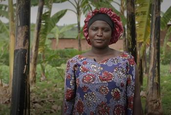 Chantal Uwizeyimana, mkazi wa Rwanda na mnufaika wa mradi wa STARLIT wa IFAD, akiwa amesimama katika shamba lake la migomba.