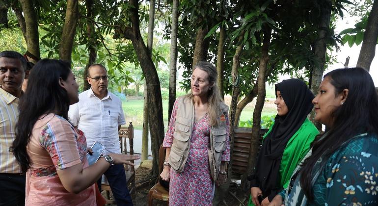 बांग्लादेश में UNFPA प्रतिनिधि, कैथरीन ब्रीन कैमकोंग (मध्य में) सुनामगंज में जलवायु अनुकूलन स्वास्थ्य प्रणाली और सामुदायिक परियोजना से जुड़ी 26 वर्षीय स्वयंसेविका शकीला बेगम (दाएँ, हरे रंग में) से मुलाक़ात करते हुए.