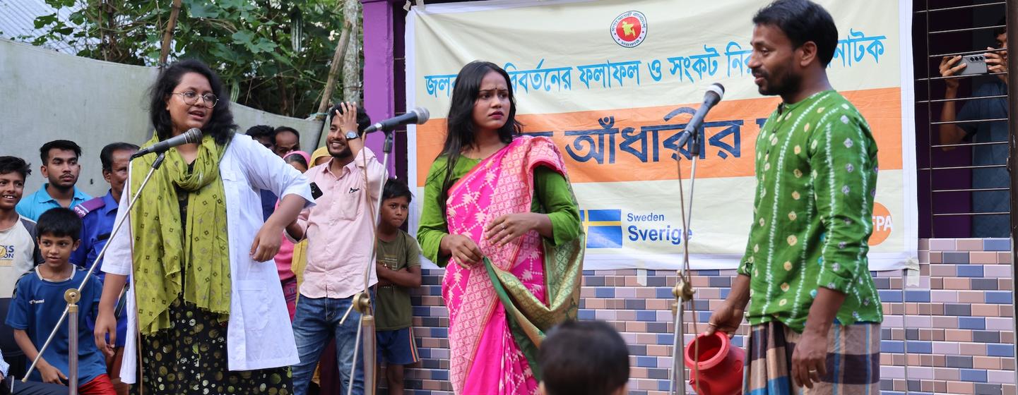  बोदिपुर, कुर्बान नगर यूनियन (सुनामगंज) में दोपहर के समय एक नुक्कड़ नाटक देखने के लिए एकत्र हुए ग्रामीण. जलवायु अनुकूलन स्वास्थ्य प्रणाली और सामुदायिक परियोजना के तहत आयोजित ये प्रस्तुतियाँ, मातृ स्वास्थ्य, स्वच्छता, आपदा की तैयारी और बाल विवाह की रोकथाम…