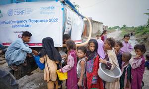 Children displaced by floods wait to collect safe drinking water in Pakistan.