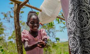 Noel-Dina washes her hands after using a latrine that her mother built.
