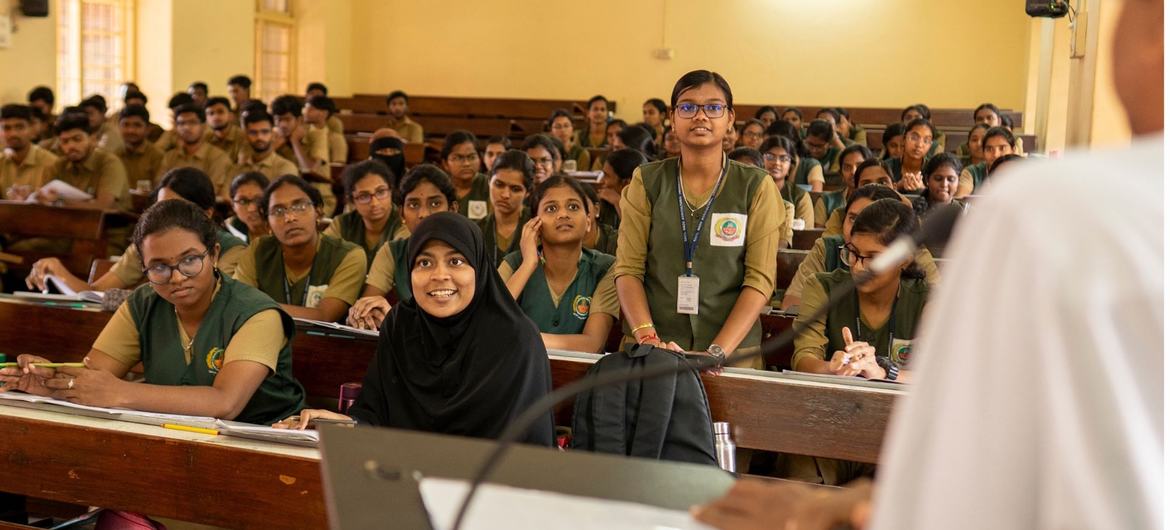 Estudantes indianos numa sala de aula universitária, ouvindo uma apresentação.