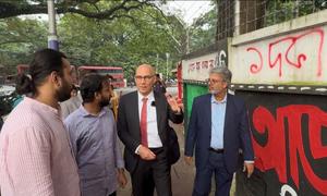 High Commissioner for Human Rights Volker Türk with students showing the grafitti made during the July protest near the Dhaka University, Bangladesh.