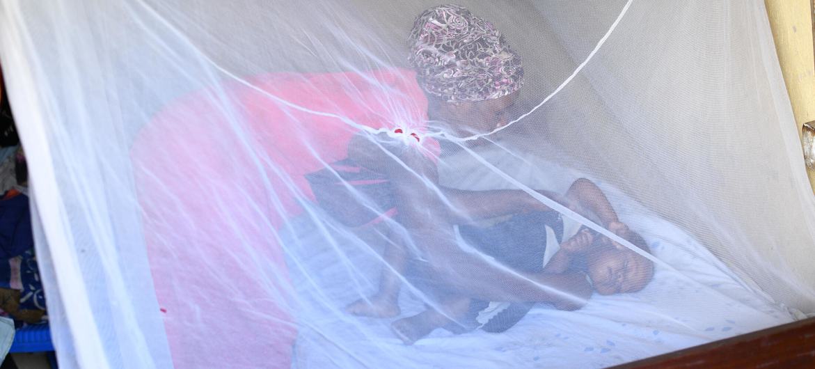 Una madre acuesta a su hijo de un año dentro de un mosquitero en una zona rural de Uganda. 