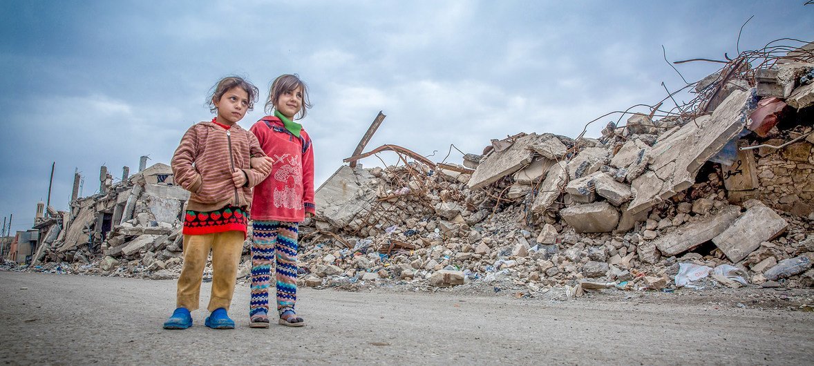 Two girls walk in the ruins of the city of Mosul.