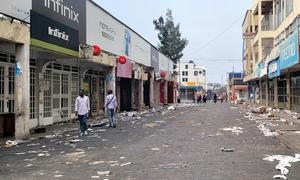 A scattering of people walk through a commercial district in Goma.