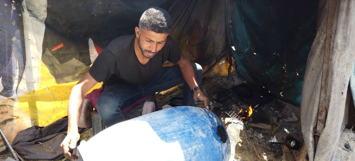 Moamen Abu Asr fixing a water tank by his tent. Moamen Abu Asr fixing a water tank by his tent.